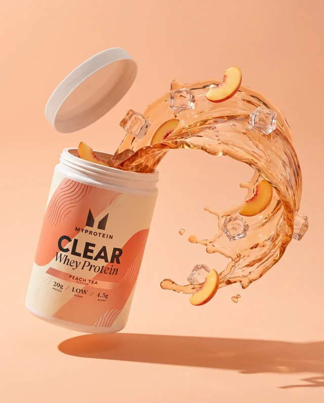 Une vague ambrée, des glaçons et des morceaux de pêche entourent le produit sur un fond abricot.